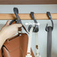 Hand holding a gray arched hanger hook on a wooden rod, 3 cm gap shown