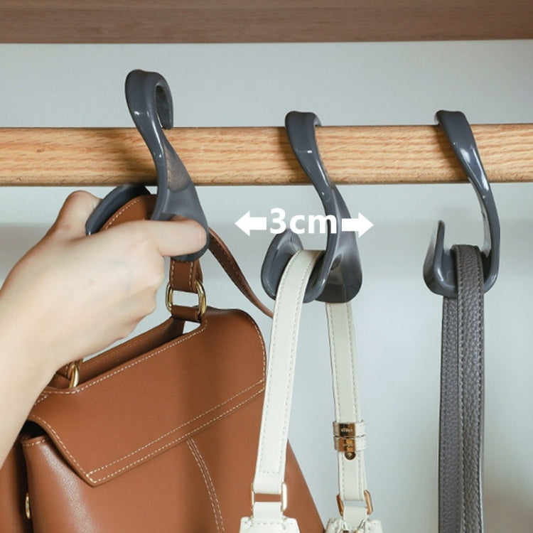 Hand holding a gray arched hanger hook on a wooden rod, 3 cm gap shown