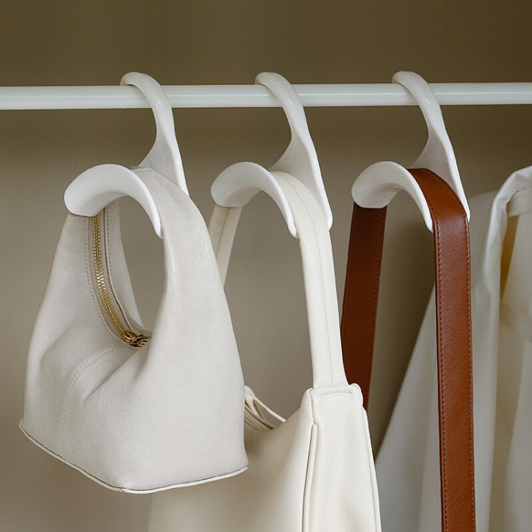 White arched hanger hooks on a rod holding handbags and accessories, set of hangers