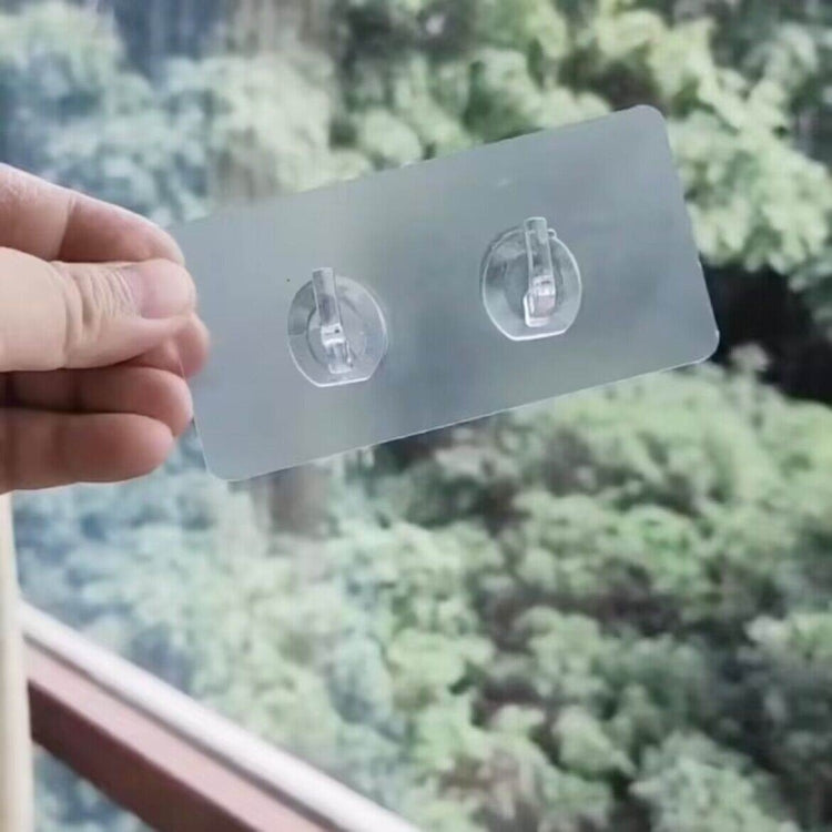 Clear double adhesive hooks on a transparent backing card held by hand