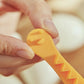 Close-up of orange lace egg cutter mold pressing into a halved egg