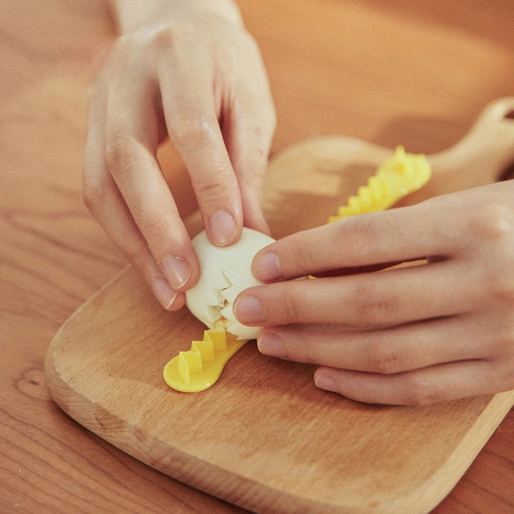 Hands shaping a halved egg using a yellow lace egg cutter mold