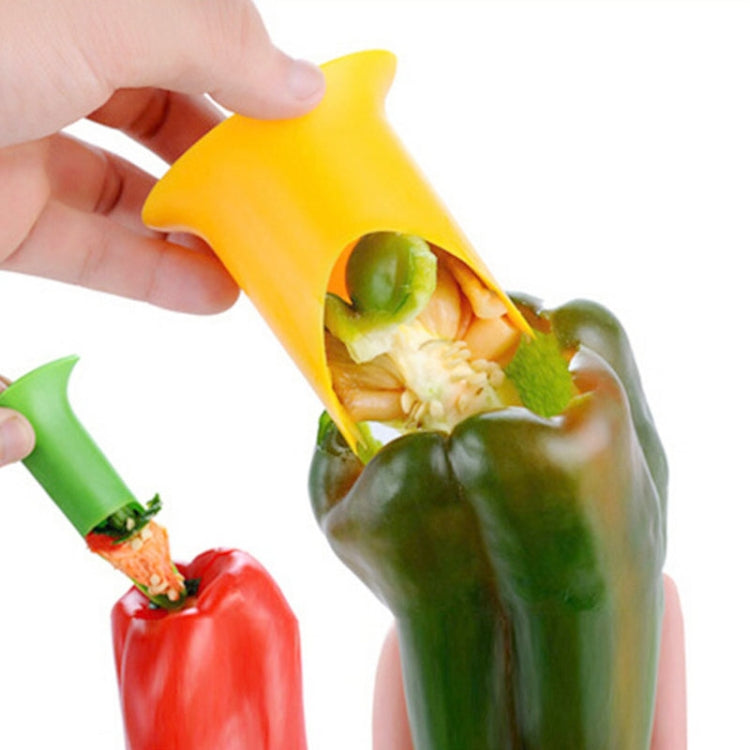 Yellow chili pepper seed extractor corer with scoop, held in hand over halved pepper.