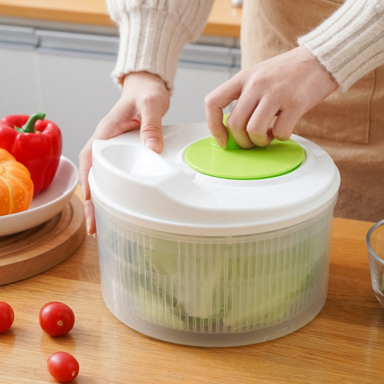 White vegetable dehydrator with green lid and mesh basket, hands closing container