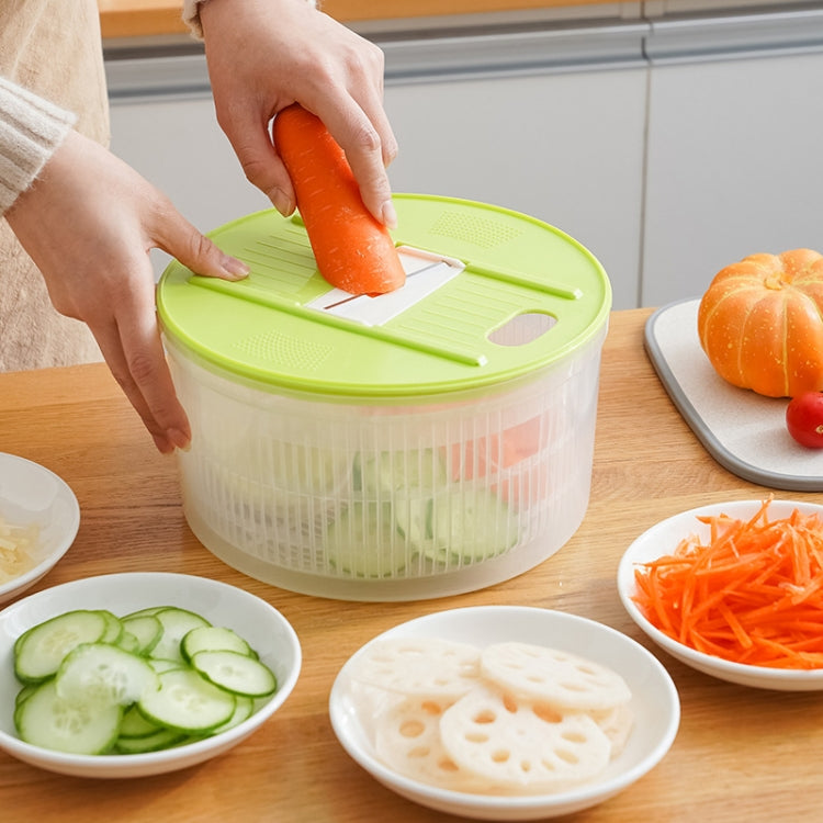 Vegetable dehydrator basket with green lid and carrot grater insert, hands slicing