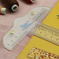 Clear plastic T-square ruler on paper with printed measurement scale and gold pins