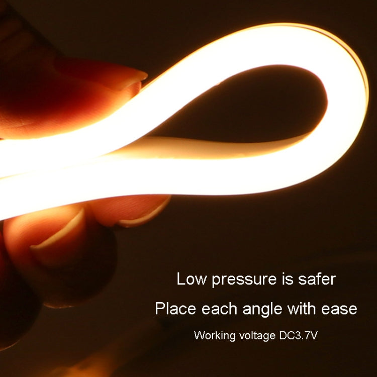 Hand holding a glowing LED strip loop with bright warm light