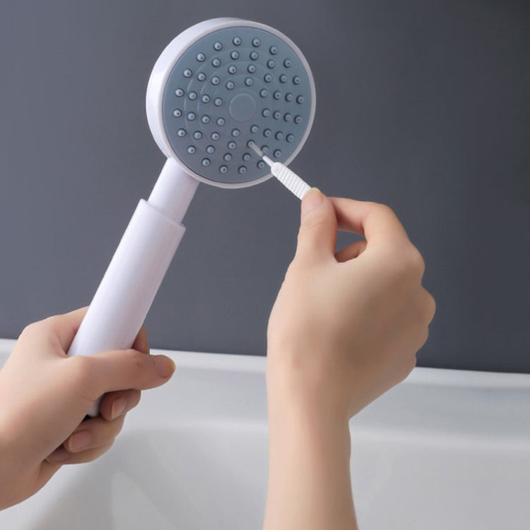 White showerhead cleaning brush scrubbing a round shower spray faceplate