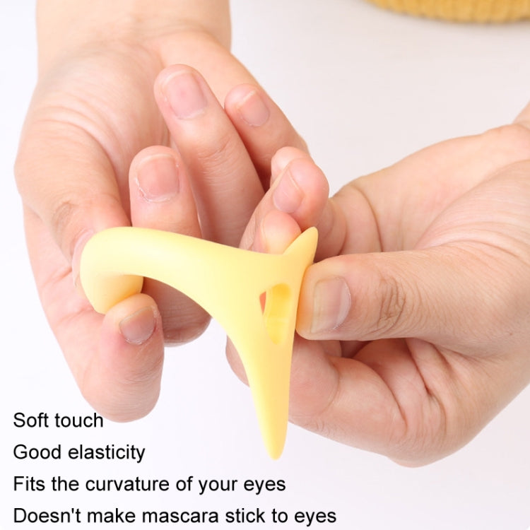 Yellow silicone eyelash guide held in hand, soft flexible spoon tip