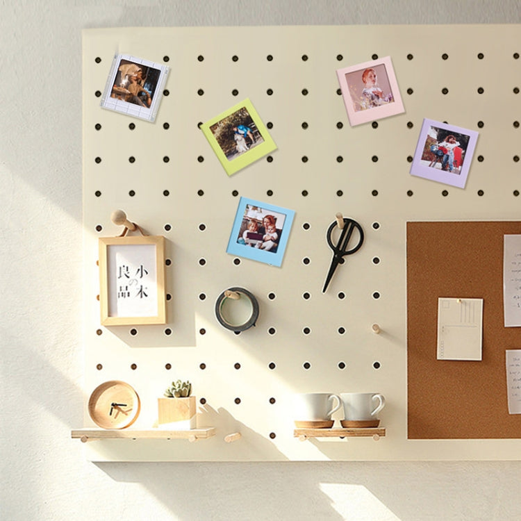 Square magnetic photo frame blocks displaying small photos on a pegboard wall