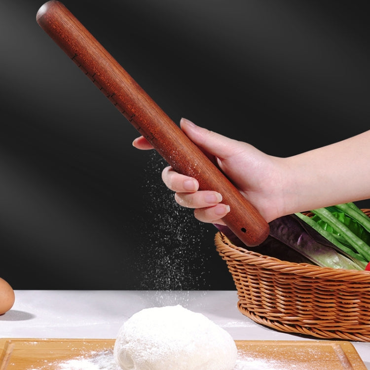 Red wooden rolling pin in hand dusted with flour, smooth dark wood grain