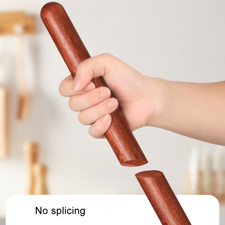 Red wooden rolling pin held in hand, smooth barrel and tapered shape