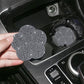 Hand holding a white rhinestone plum blossom car water coaster by the cup holder