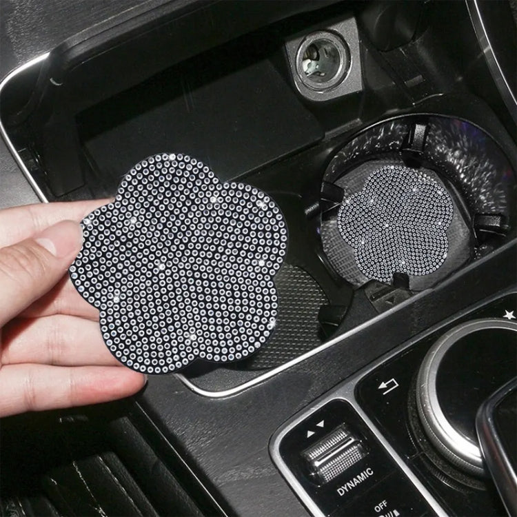 Hand holding a white rhinestone plum blossom car water coaster by the cup holder