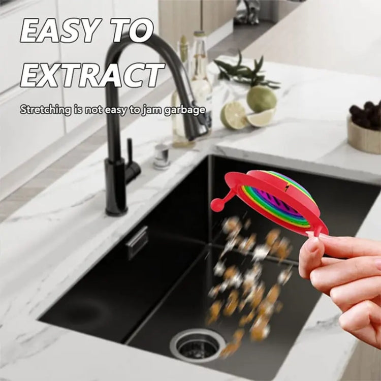 Retractable rainbow monster strainer being pulled from kitchen sink drain, red rim