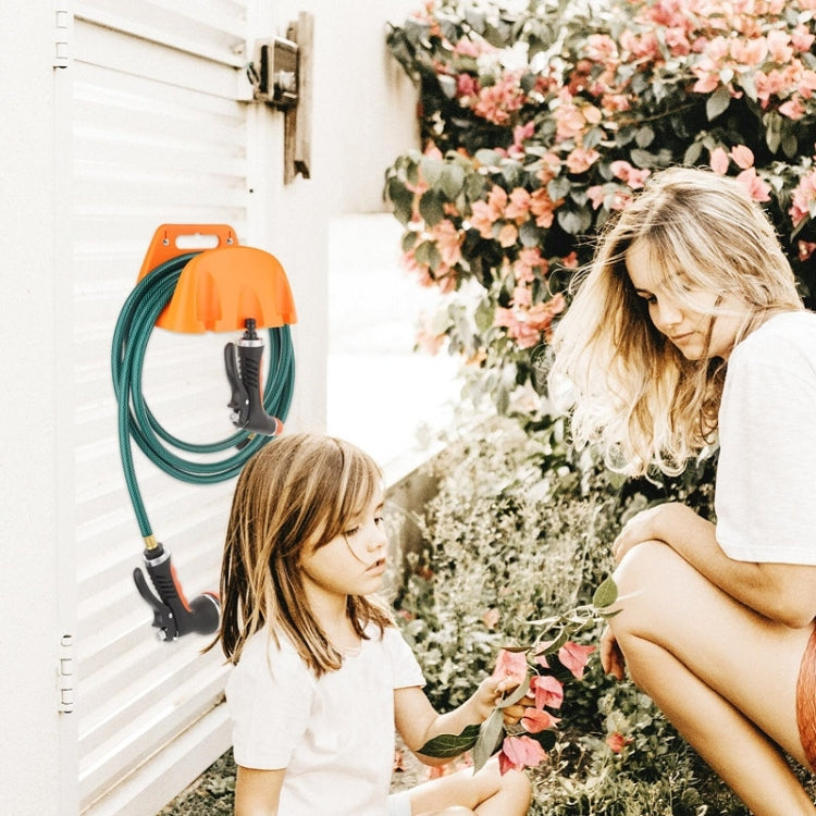 Orange plastic wall-mounted hose holder holding green garden hoses with black connectors