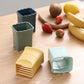 Set of vegetable slicing cup tools in green, light blue, blue, and yellow, open top