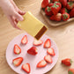 Yellow cup slicer held above plate with strawberry slices