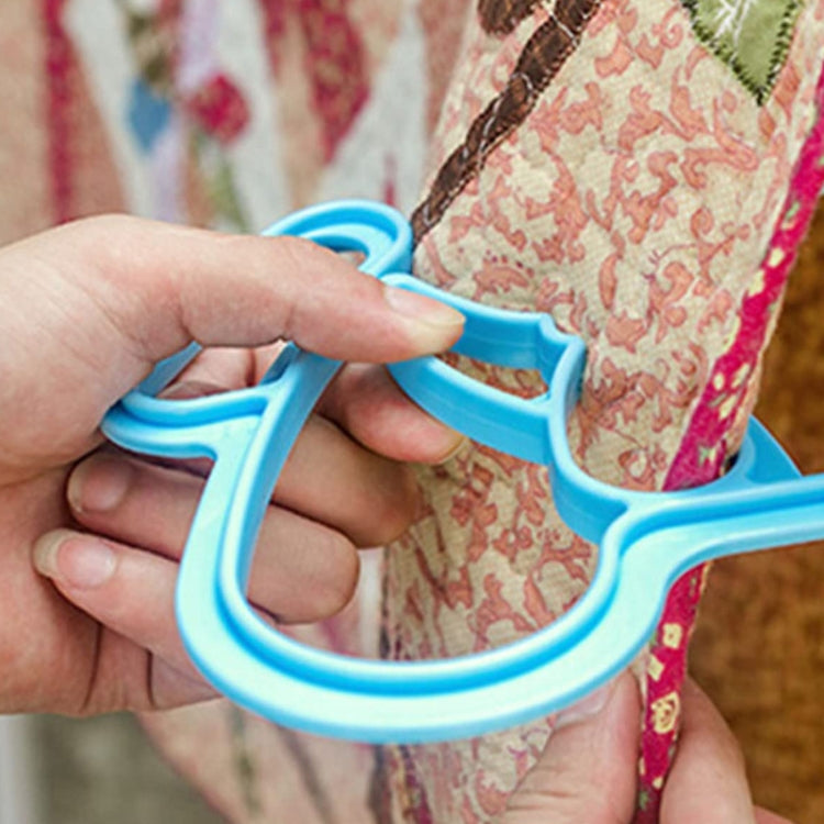 Blue plastic quilt clip being held by hand for securing duvet fabric