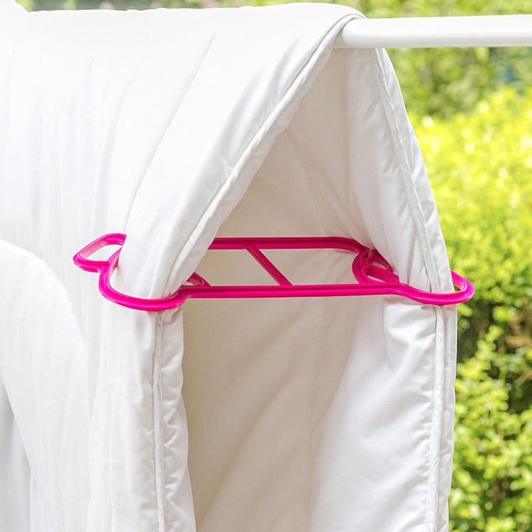 Pink plastic quilt clip securing white duvet on a drying rack bar