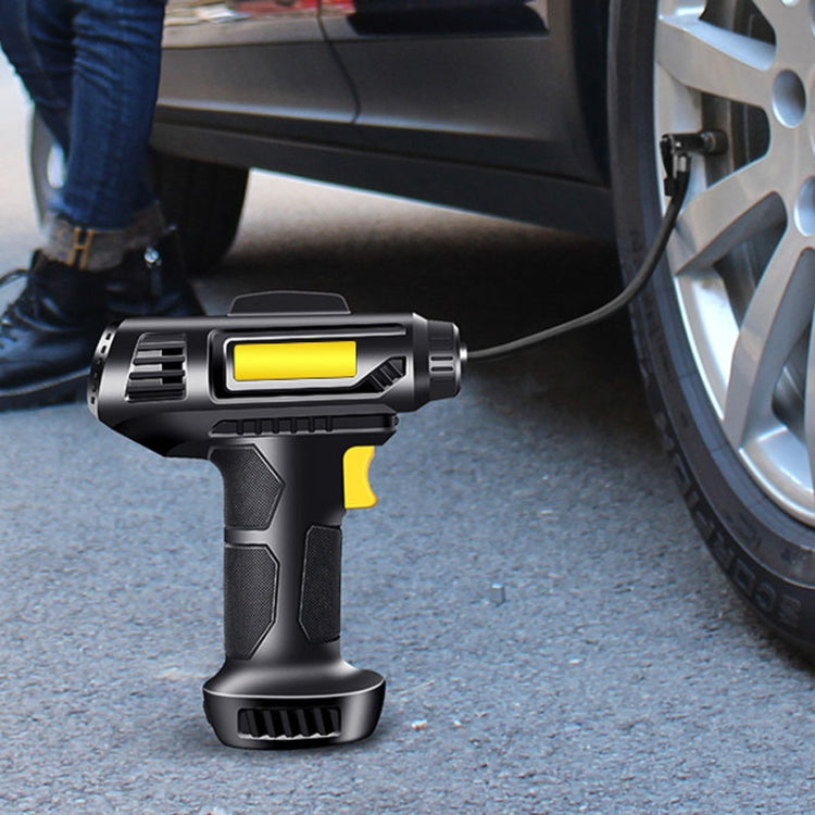 Portable car tire inflator with yellow button and nozzle near a vehicle wheel