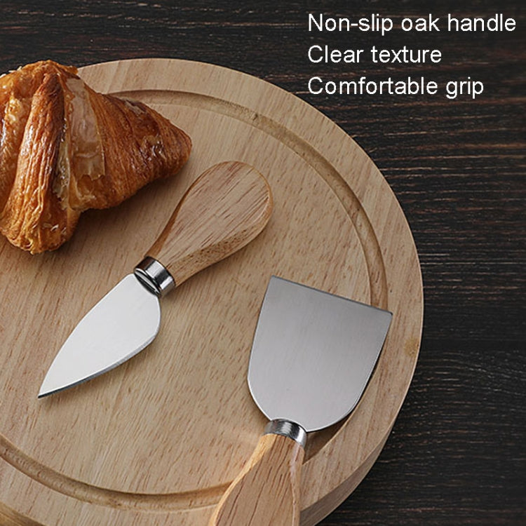 Oak cheese tools set with stainless knives and spatulas on a round wooden board