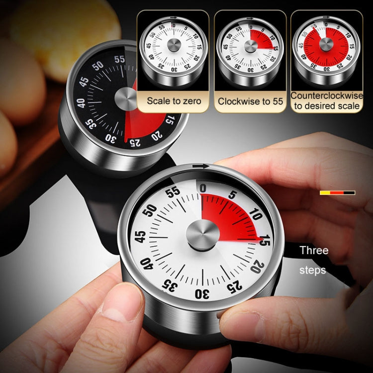 Stainless steel mechanical kitchen timer with red dial markings, held in hands