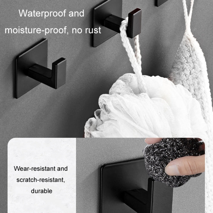 Multiple black wall hooks holding a white towel with hanging loops