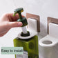 Hand installing a wall-mounted soap dispenser holder with adhesive patch, white