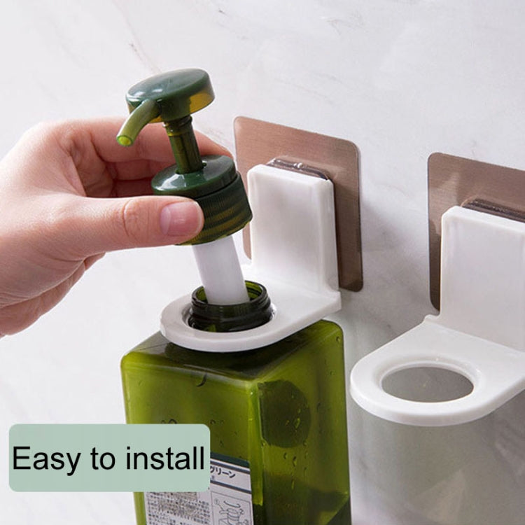 Hand installing a wall-mounted soap dispenser holder with adhesive patch, white