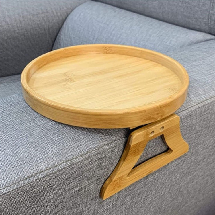Round wooden tray with foldable supports sitting on a gray fabric sofa.