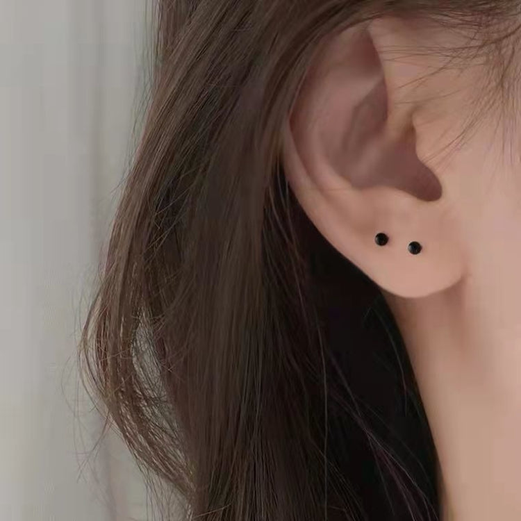Black plastic stud earrings on ear, small round posts with dot backs