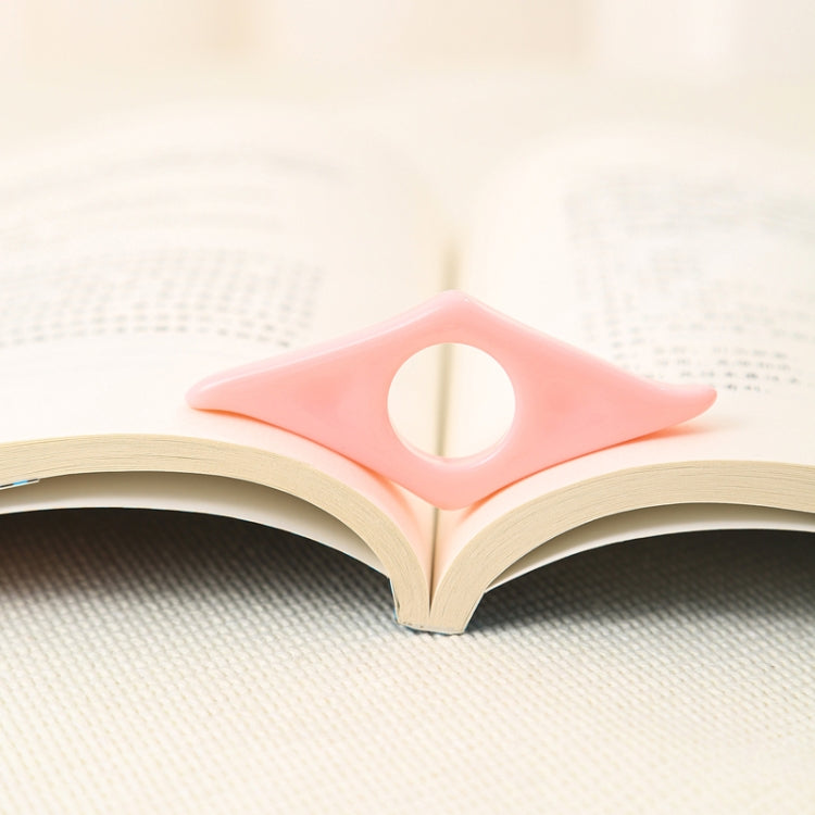 Pink acrylic thumb bookmark placed in an open book to hold a page.