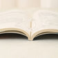 Transparent acrylic thumb bookmark clipped at the page edge of an open book.