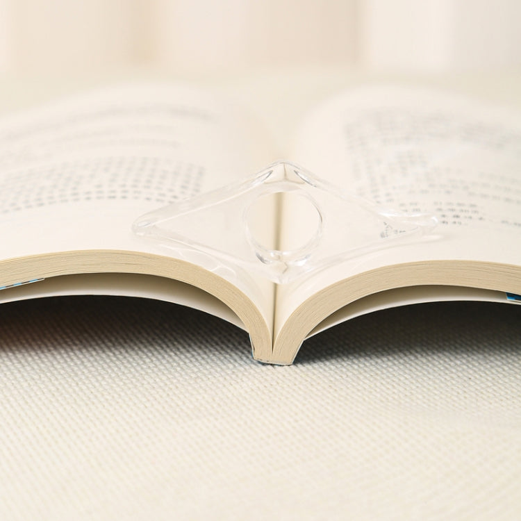 Transparent acrylic thumb bookmark clipped at the page edge of an open book.