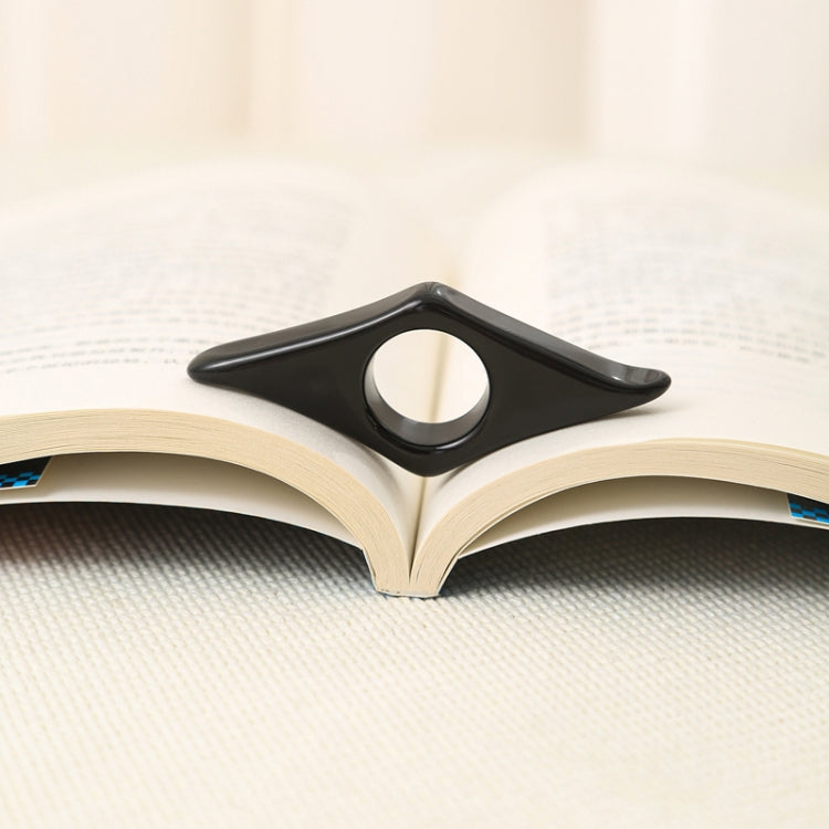 Black acrylic thumb bookmark resting in an open book page edge.