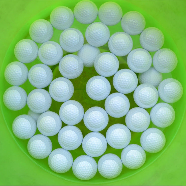 White floating golf practice balls in a green bowl, dimpled texture