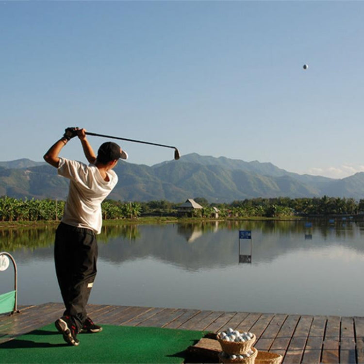 Golfer practicing on an outdoor dock beside a calm water training area