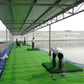 Covered indoor water driving range with green hitting mats by a lake