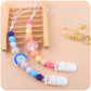 Two baby pacifier clips with silicone beads and rainbow charms; white holders