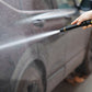 Handheld water jet car wash nozzle spraying a stream onto a vehicle door