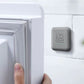 Gray square silicone door bumper pad with embossed logo, mounted on door edge