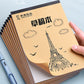 Beige blank sketch notebook cover with Eiffel Tower line art, clouds, and birds, held in hand