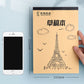 Beige sketch notebook with Eiffel Tower and cloud illustrations on the front cover, held