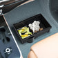 Car armrest storage box holding snacks and crumpled tissues in open bin
