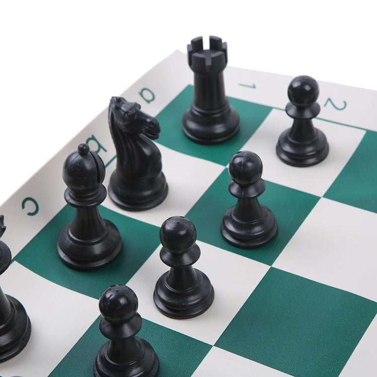 Foldable portable chess set close-up of black chess pieces on green-and-white squares