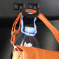 Black trunk seat button hook with orange strap holding a bottle.