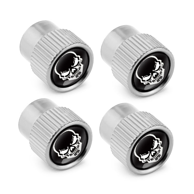 Four silver valve caps featuring black skull emblem discs, angled close view
