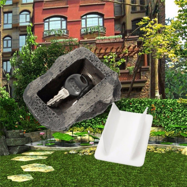 Rock-style key hiding box shaped like a pine nut with open white insert in yard