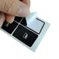 Hand applying black window switch button repair sticker with white icon